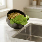 Scolapasta in silicone verde agganciato a una pentola piena di fusilli